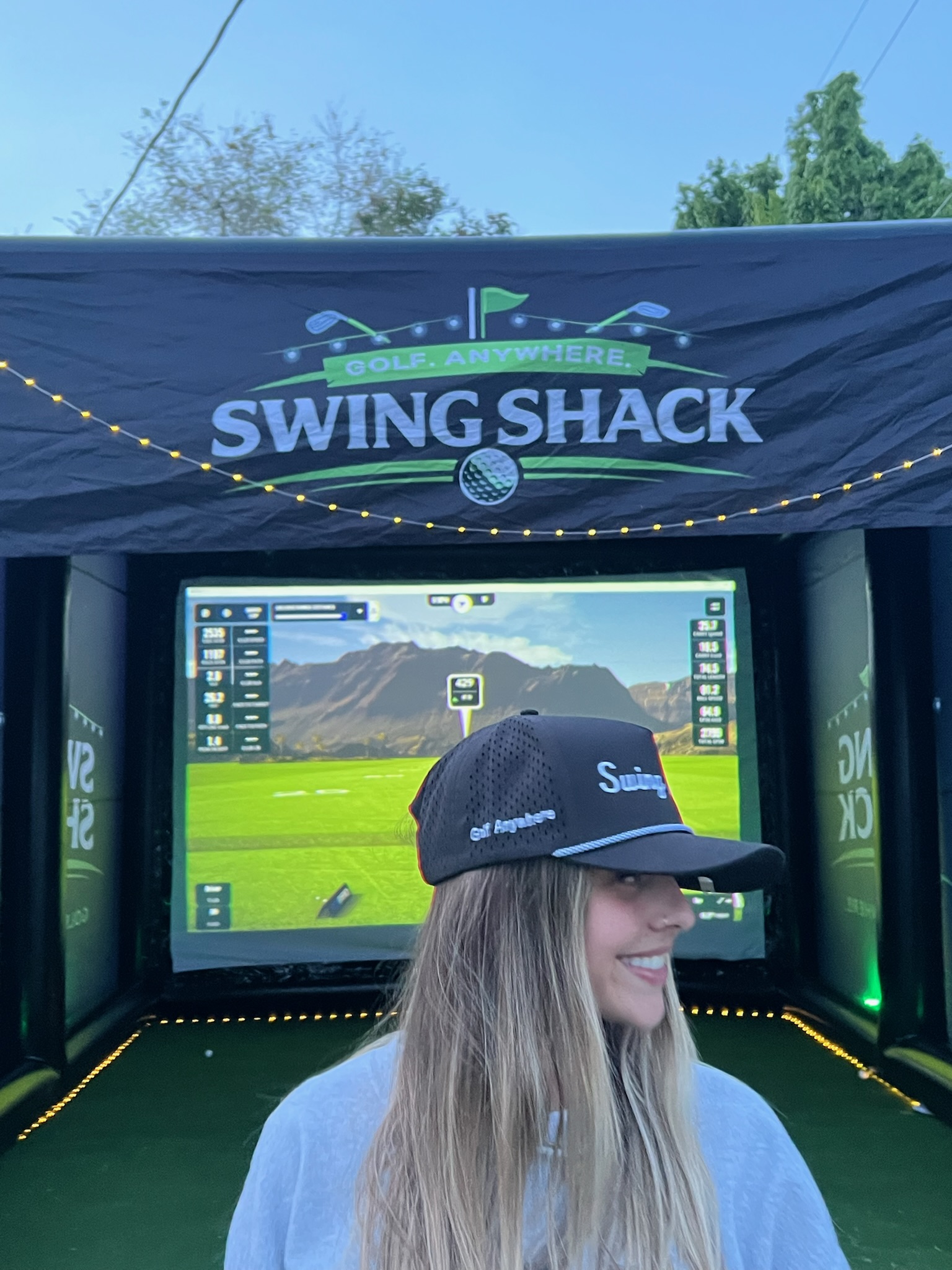 Guest smiling in a Swing Shack hat at an event